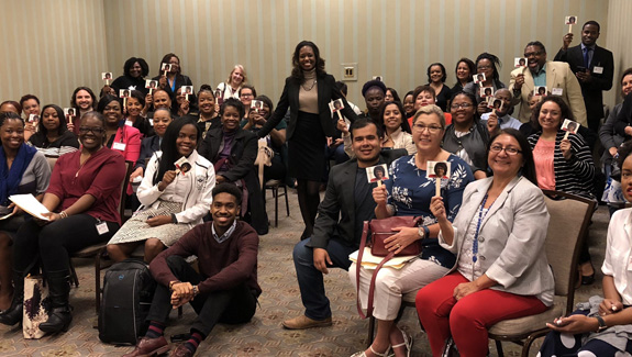 woman-stephanie-bension-standing-in-group-of men-and-women-sitting